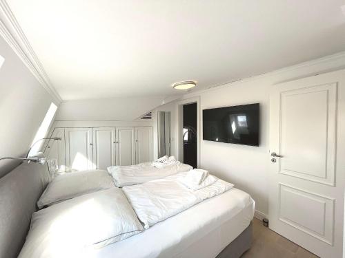 a white bed in a room with a tv at Sylter Auberge im Haus Mateika in Westerland