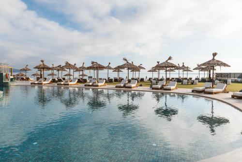 a swimming pool with lounge chairs and umbrellas at Pepper Sea Club Hotel in Georgioupolis
