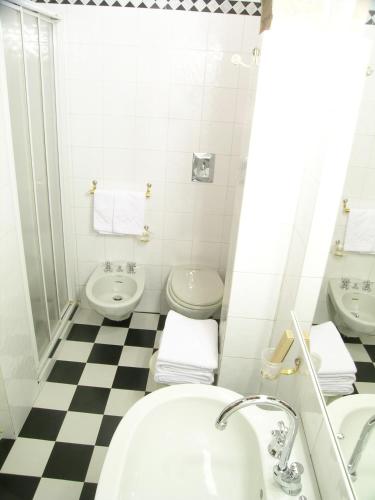 a bathroom with two toilets and a sink and a tub at Hotel Monteriggioni in Monteriggioni