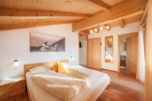 two beds in a bedroom with wooden ceilings at Tonigbauernhof Enzian in Schenna