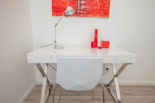 - un bureau blanc avec une lampe et une chaise blanche dans l'établissement Sublime trois pièces proche Monaco, à Beausoleil