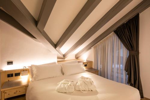 a bedroom with a white bedspread and white pillows at Hotel Medil in Campitello di Fassa