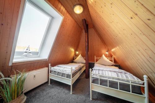 two beds in a attic room with a window at "Villa Anker" Dachgeschoss - links in Fehmarn