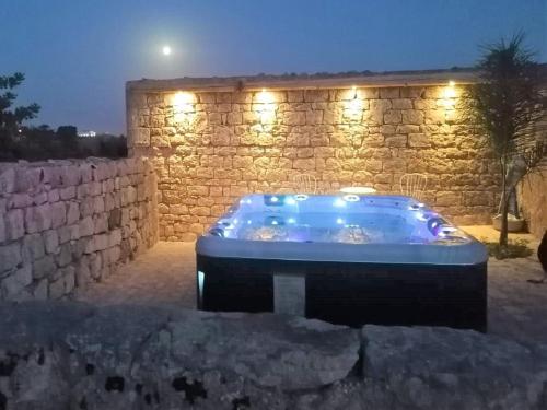 una vasca idromassaggio di fronte a un muro di pietra con luci di Il Baglio di Kharrub rural guest house a Pozzallo