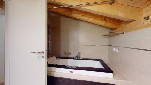 a bathroom with a bath tub in a room at Chesa Seraina Abitaziun Seraina 8 - Tabacco - Madulain in Madulain