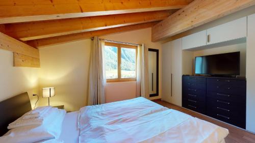 a bedroom with a bed with a television and a dresser at Chesa Seraina Abitaziun Seraina 9 - Mahogany - Madulain in Madulain