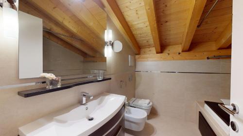 a bathroom with a white sink and a toilet at Chesa Seraina Abitaziun Seraina 9 - Mahogany - Madulain in Madulain