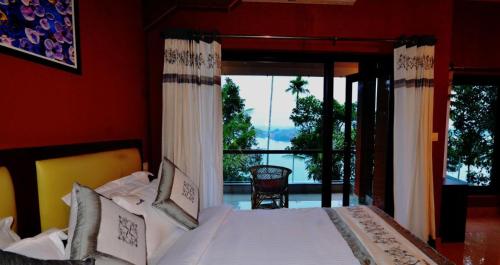 una camera da letto con un letto e una grande finestra di LakeRose Wayanad Resort - Lake view a Kalpetta