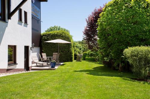 a lawn with a table and an umbrella in a yard at Gästehaus Prinzregent Luitpold in Bad Steben