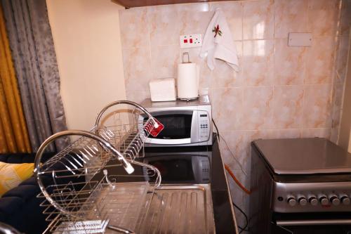 a small kitchen with a microwave on a counter at Tom Mboya Estate - Fast WI-FI, Netflix and Parking 1Br Apartment in Kisumu Town in Kisumu