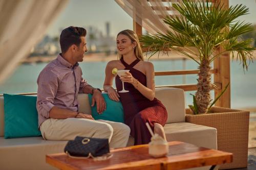 a man and a woman sitting on a couch at Grand Hyatt Doha Hotel & Villas in Doha