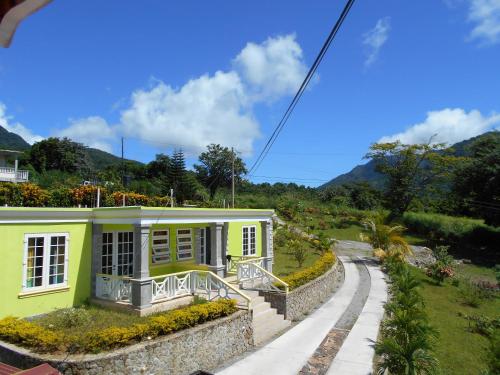 a small yellow house with a road leading to it at Diamond View Cottages in Roseau