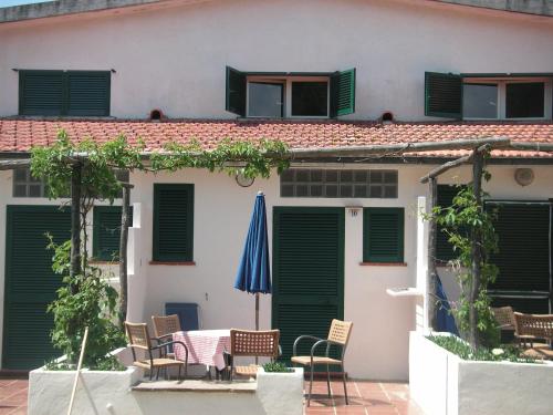 a house with a table and chairs and a blue umbrella at Azienda Agricola Sapereta in Porto Azzurro