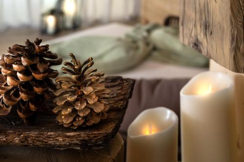 a table with two candles and two pine cones at Cesa Edelweiss Living & Spa in Campitello di Fassa