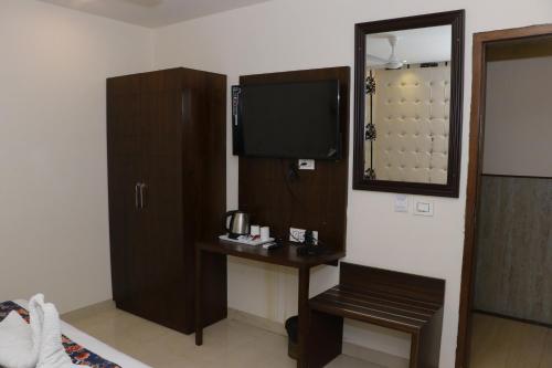 een kamer met een bureau met een spiegel en een televisie bij Hotel S C Residency in Zirakpur