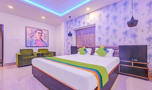 a bedroom with a large bed and a chair at Treebo The Bollywood in Bhubaneshwar