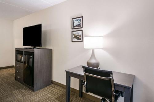 a room with a desk with a television and a chair at Clarion Pointe Jamestown - Falconer in Jamestown