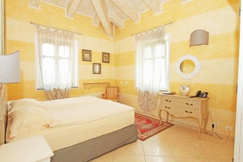 a bedroom with a bed and a dresser and windows at Villa Morneto in Vignale