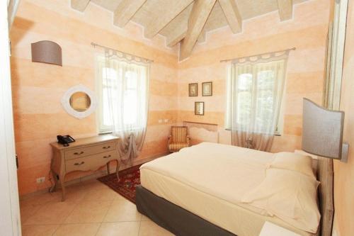 a bedroom with a bed and a dresser and windows at Villa Morneto - Adults Only in Vignale Monferrato