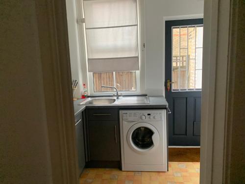 a kitchen with a washing machine and a sink at Unique 2 bedroom apartment in London/ Excel / Olympic city close to central line tube station with gated parking space in London