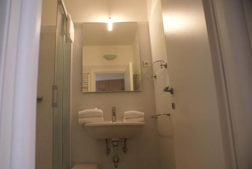 ein weißes Badezimmer mit einem Waschbecken und einem Spiegel in der Unterkunft Appartementanlage Bach in Bad Kleinkirchheim