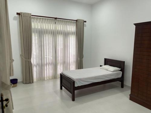 a bedroom with a bed and a window with curtains at Murphy's Villa in Katunayaka