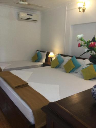 a hotel room with two beds and a vase of flowers at Anthy’s Guesthouse and Restaurant in Benaulim