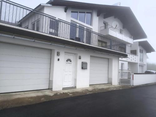 een wit huis met twee garagedeuren en een balkon bij Appartment am Egghof in Oberperfuss