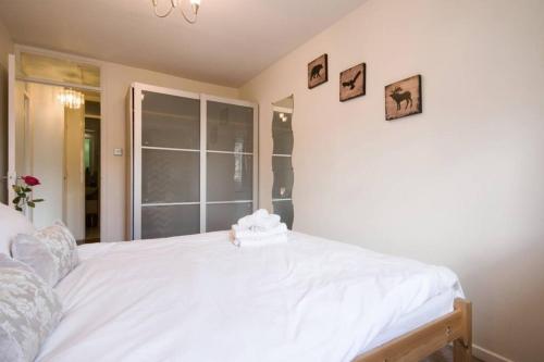 a white bed in a bedroom with pictures on the wall at 1 bedroom, self check-in, central and quiet apartment up to 3 in Newbury in Newbury