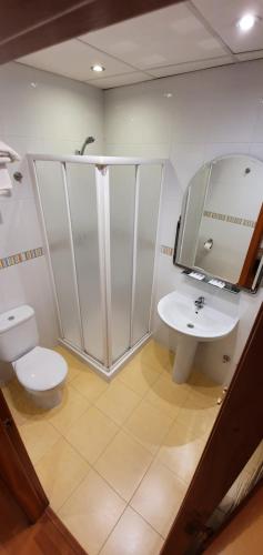 een badkamer met een toilet, een wastafel en een spiegel bij Hotel La Curva in Albolote