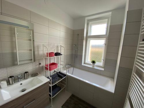 a bathroom with a tub and a sink and a window at Apartman Xaveriova in Prague