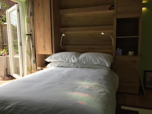 a large bed with a wooden headboard and white pillows at The Barn in South Hayling