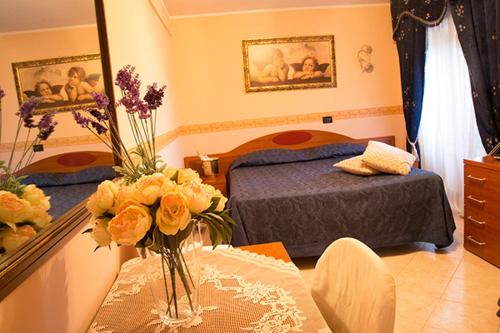 a bedroom with a bed and a table with a vase of flowers at Villa Altieri in Albano Laziale