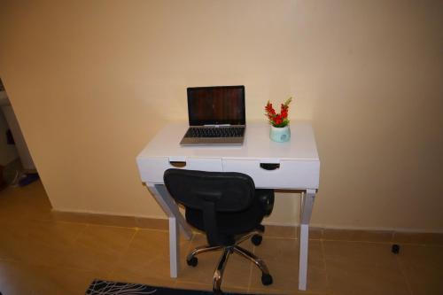 a desk with a laptop computer on it with a chair at Tom Mboya Estate - Fast WI-FI, Netflix and Parking 1Br Apartment in Kisumu Town in Kisumu