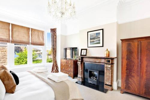 a bedroom with a fireplace and a bed and a chandelier at Central Harrogate townhouse apartment with parking in Harrogate