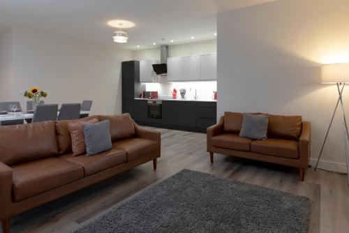 sala de estar con 2 sofás marrones y cocina en Pembroke Self Catering Apartments, en Pembroke