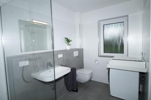 ein weißes Bad mit einem Waschbecken und einem WC in der Unterkunft Ferienhaus Sonnenblick mit Sauna Harkebrügger See in Barßel