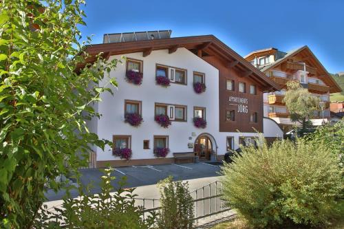 a white building with flowers on the windows at Appartements Haus JÖRG in Serfaus
