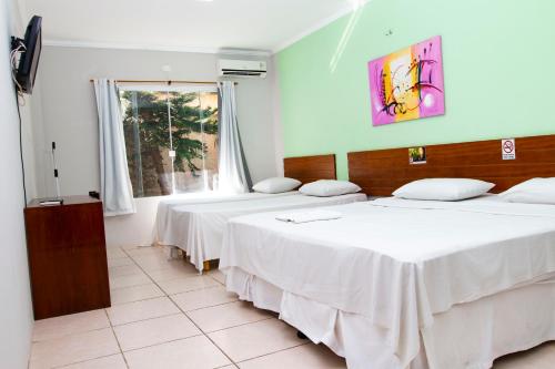 two beds in a room with a window at Hotel Portal dos Ventos in Parnaíba