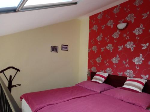 1 dormitorio con 2 camas y pared roja en Borostyán Vendégház Eger en Eger