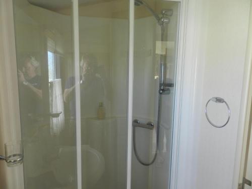 a man taking a picture of a shower in a bathroom at Cwtch Caravans in Little Haven