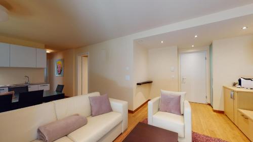 a living room with a white couch and a kitchen at Chesa Seraina Abitaziun Seraina 2 - Ivory - Madulain in Madulain