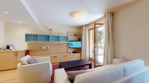 a living room with a white couch and a kitchen at Chesa Seraina Abitaziun Seraina 2 - Ivory - Madulain in Madulain