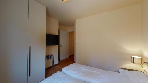 a bedroom with a bed and a white wall at Chesa Seraina Abitaziun Seraina 2 - Ivory - Madulain in Madulain