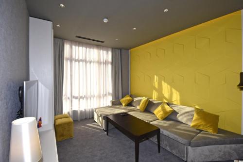 a living room with a couch and a yellow wall at Avenue ApartHotel in Yerevan