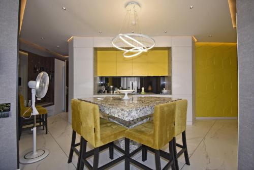 a kitchen with a dining table and yellow chairs at Avenue ApartHotel in Yerevan