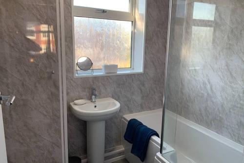 ein Bad mit einem Waschbecken, einem WC und einem Fenster in der Unterkunft Modern fully refurbished 3 bedroom home in Blackpool