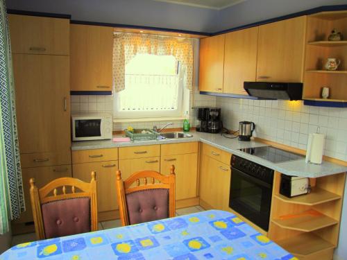 a kitchen with wooden cabinets and a table and chairs at Ferienwohnung Mauer, Wohnung "C" in Heede
