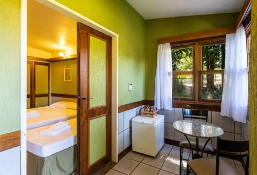 a room with a bed and a table and a window at Hotel Estância Barra Bonita in Barra Bonita