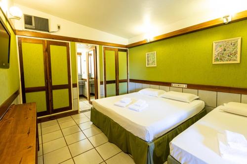 two beds in a room with green walls at Hotel Estância Barra Bonita in Barra Bonita